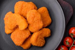 deliciosos nuggets de pollo crujientes y frescos sobre un fondo de hormigón oscuro foto