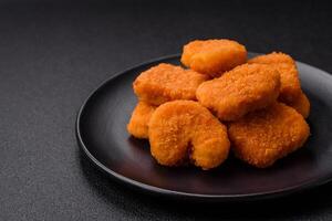 Delicious fresh crispy chicken nuggets on a dark concrete background photo