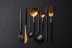 Cutlery fork, knife and spoon on a dark textured concrete background photo