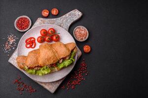 Delicious fresh crispy croissant with chicken or beef meat, lettuce, tomatoes, spices and sauce photo