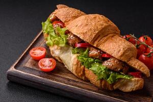 Delicious fresh crispy croissant with chicken or beef meat, lettuce, tomatoes, spices and sauce photo