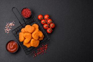 Delicious fresh crispy chicken nuggets on a dark concrete background photo