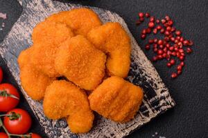 Delicious fresh crispy chicken nuggets on a dark concrete background photo