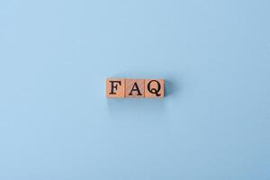 The inscription FAQ made up of wooden cubes on a plain background photo