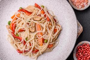 Delicious rice noodles or udon with chicken, carrots, pepper, salt, spices and herbs photo