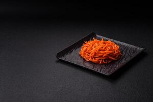 Tasty spicy Korean carrot with spices and herbs on a dark concrete background photo