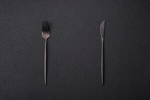 Cutlery fork, knife and spoon on a dark textured concrete background photo