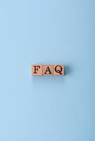 The inscription FAQ made up of wooden cubes on a plain background photo