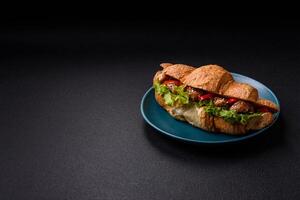 Delicious fresh crispy croissant with chicken or beef meat, lettuce, tomatoes, spices and sauce photo