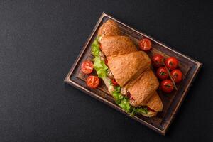 Delicious fresh crispy croissant with chicken or beef meat, lettuce, tomatoes, spices and sauce photo