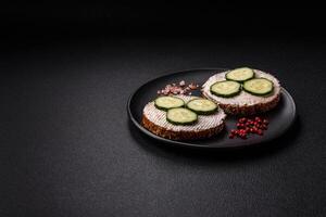 Delicious vegetarian sandwich with grilled toast, cream cheese, cucumbers and seeds photo