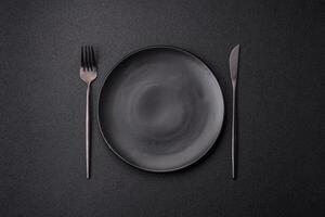 Cutlery fork, knife and spoon on a dark textured concrete background photo