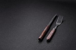 Cutlery fork, knife and spoon on a dark textured concrete background photo