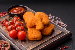 Delicious fresh crispy chicken nuggets on a dark concrete background photo