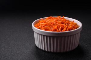 Tasty spicy Korean carrot with spices and herbs on a dark concrete background photo