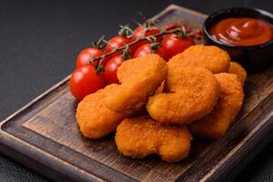 Delicious fresh crispy chicken nuggets on a dark concrete background photo