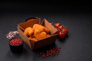 Delicious fresh crispy chicken nuggets on a dark concrete background photo