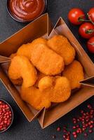 Delicious fresh crispy chicken nuggets on a dark concrete background photo