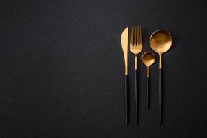 Cutlery fork, knife and spoon on a dark textured concrete background photo