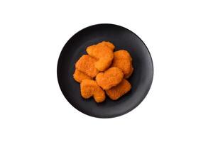 Delicious fresh crispy chicken nuggets on a dark concrete background photo