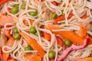 Delicious rice noodles or udon with chicken, carrots, pepper, salt, spices and herbs photo