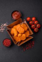 Delicious fresh crispy chicken nuggets on a dark concrete background photo