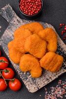 Delicious fresh crispy chicken nuggets on a dark concrete background photo