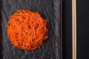 Tasty spicy Korean carrot with spices and herbs on a dark concrete background photo