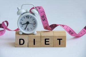 Diet text on wooden cube with alarm clock and measuring tape background. Diet and fitness concept. photo