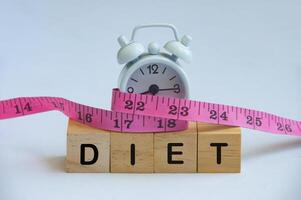 Diet text on wooden cube with alarm clock covered by measuring tape. Diet and fitness concept. photo