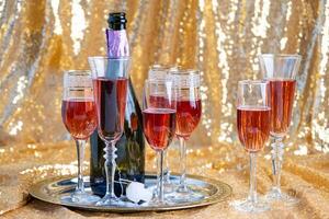 glasses of rose champagne on sparkling golden cloth photo