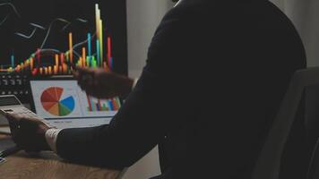 Businessman analyzing a graphic of a stock exchange chart. Back of the head of a young male businessman looking at a stock diagram on the big screen of the computer video