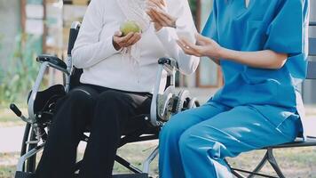 Midsection of female nurse checking blood pressure of woman sitting on wheelchair in clinic video