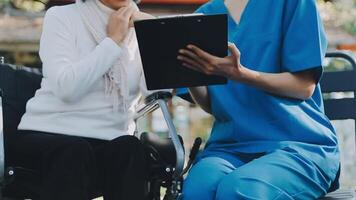 Midsection of female nurse checking blood pressure of woman sitting on wheelchair in clinic video