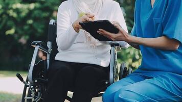 Midsection of female nurse checking blood pressure of woman sitting on wheelchair in clinic video