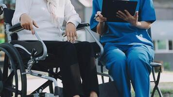 Midsection of female nurse checking blood pressure of woman sitting on wheelchair in clinic video