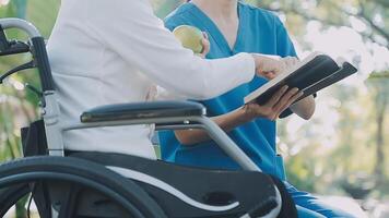 Midsection of female nurse checking blood pressure of woman sitting on wheelchair in clinic video