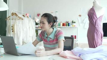 een gelukkig vrouw ondernemer in haar studio is maken nieuw kleding collecties van haar ontwerp. video