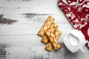 Glazed puff pastry Sfogliatine Glassate and cup of milk on white background, top view photo