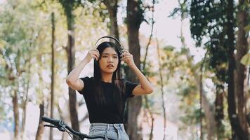 Lebensstil, Ausbildung, Jugend. Teenager Schüler im Kopfhörer mit Smartphone Fahrrad Sitzung im Park, weiblich sieht aus beim Telefon Bildschirm video