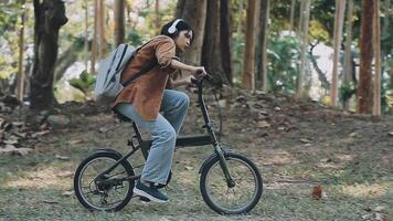 estilo de vida, educación, adolescencia. Adolescente estudiante en auriculares con teléfono inteligente bicicleta sentado en parque, hembra mira a teléfono pantalla video