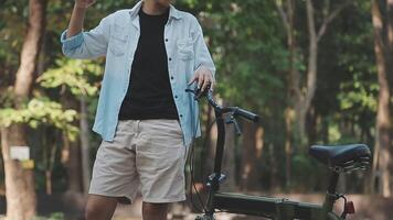 estilo de vida, educación, adolescencia. Adolescente estudiante en auriculares con teléfono inteligente bicicleta sentado en parque, hembra mira a teléfono pantalla video