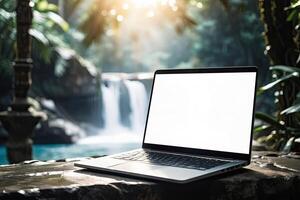 AI generated Laptop with blank white screen mock up on mountain lake in the rocks with waterfall in the tropical jungle. Remote work on vacation and travel, home office, internet, tours, trekking photo