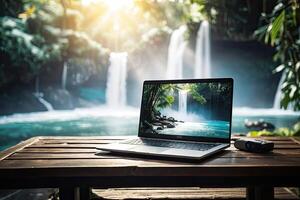AI generated Laptop with waterfall in the tropical jungle wallpaper on table on a mountain lake in the rocks with waterfall. Remote work on vacation and travel, home office, internet, tours, trekking. photo
