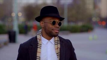 elegante legal masculino artista vestindo uma chapéu e oculos de sol dentro a cidade ruas video