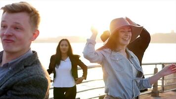 verschillend groep van jong mensen dansen samen buiten Bij zonsondergang video