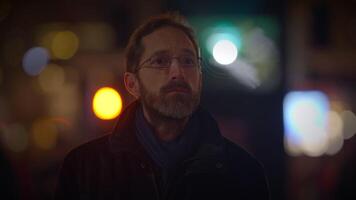 Jeune homme avec des lunettes en train de regarder lumière spectacle dans le ville à nuit video