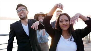 diverso gruppo di giovane persone danza insieme al di fuori a tramonto video