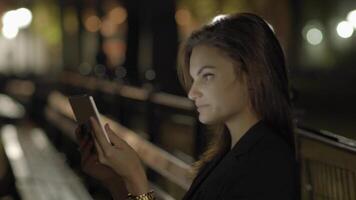 ung kvinna använder sig av läsplatta dator i de parkera på natt video