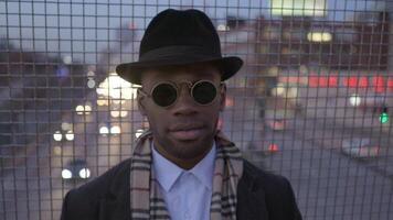 de moda frio masculino artista vistiendo un sombrero y Gafas de sol en el ciudad calles video